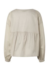 Blouse beige clair à manches longues avec un détail froncé dans le dos et des poignets élastiques aux manches.