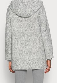 Szary płaszcz o wzorze jodełki z kapturem, luźnym krojem i szerokimi rękawami. Teksturowana tkanina z widocznymi przeszyciami.