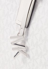 Witte leren tas met een textuur oppervlak. Voorzien van een zilverkleurige metalen ritssluiting in de vorm van de letters M, K en W, bevestigd met een bandje.