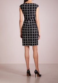 Black and white checkered dress with cap sleeves, fitted waist, and knee-length hem, paired with black high heels. Smooth texture.
