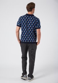 Navy ja vaalean sininen kuvioitu poolopaita, lyhyt hiha, jossa ribbireunus. Yhdistetty harmaisiin housuihin ja rentoihin lenkkareihin.