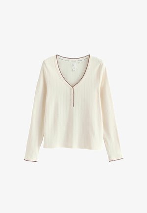 Kremasta dugorukava majica s rebrastom teksturom, V-izrezom i bordo detaljima duž izreza i rukava. Horizontalni uzorak.