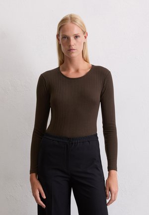 Bruin geribde longsleeve top met een ronde halslijn, gecombineerd met zwarte pantalons met elastische taille. De stof lijkt rekbaar en aansluitend.