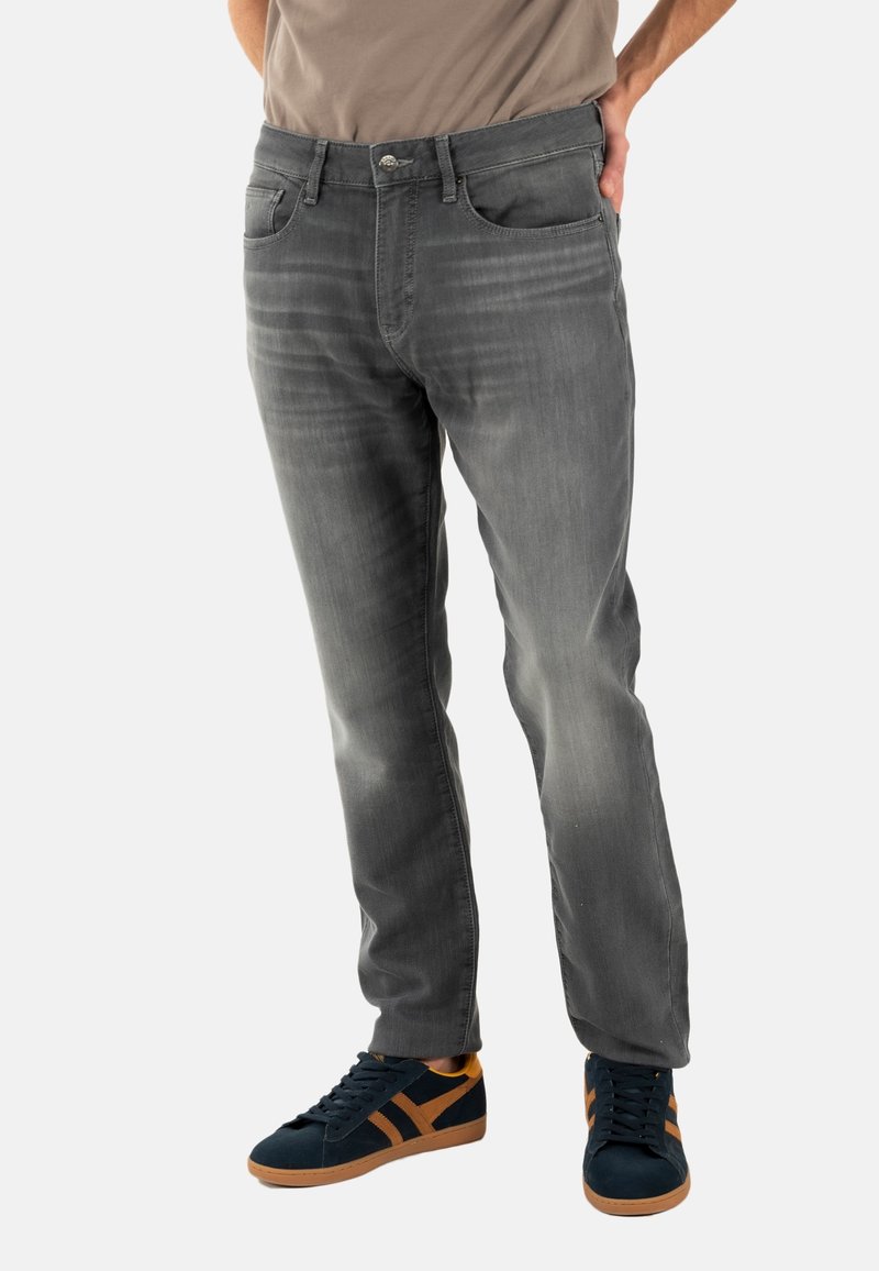 Jeans de denim gris con corte recto, presentan un lavado deslavado, cinco bolsillos y un sutil efecto de desgaste. Combinados con zapatillas navy con detalles en naranja.