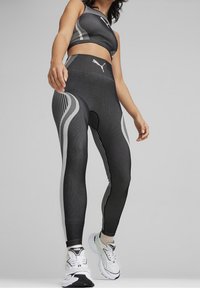 Sportswear sæt med sorte og hvide leggings med horisontale striber og mesh-detaljer, parret med en matchende crop top.