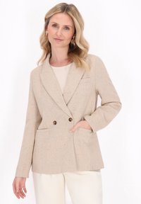 Blazer beige doppiopetto in tessuto testurizzato, con due tasche frontali e sottili macchie colorate. Design del rever a trama nota.