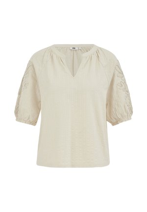 Blouse couleur crème avec des manches bouffantes jusqu'au coude, des détails floraux brodés sur les manches, et un petit col en v.