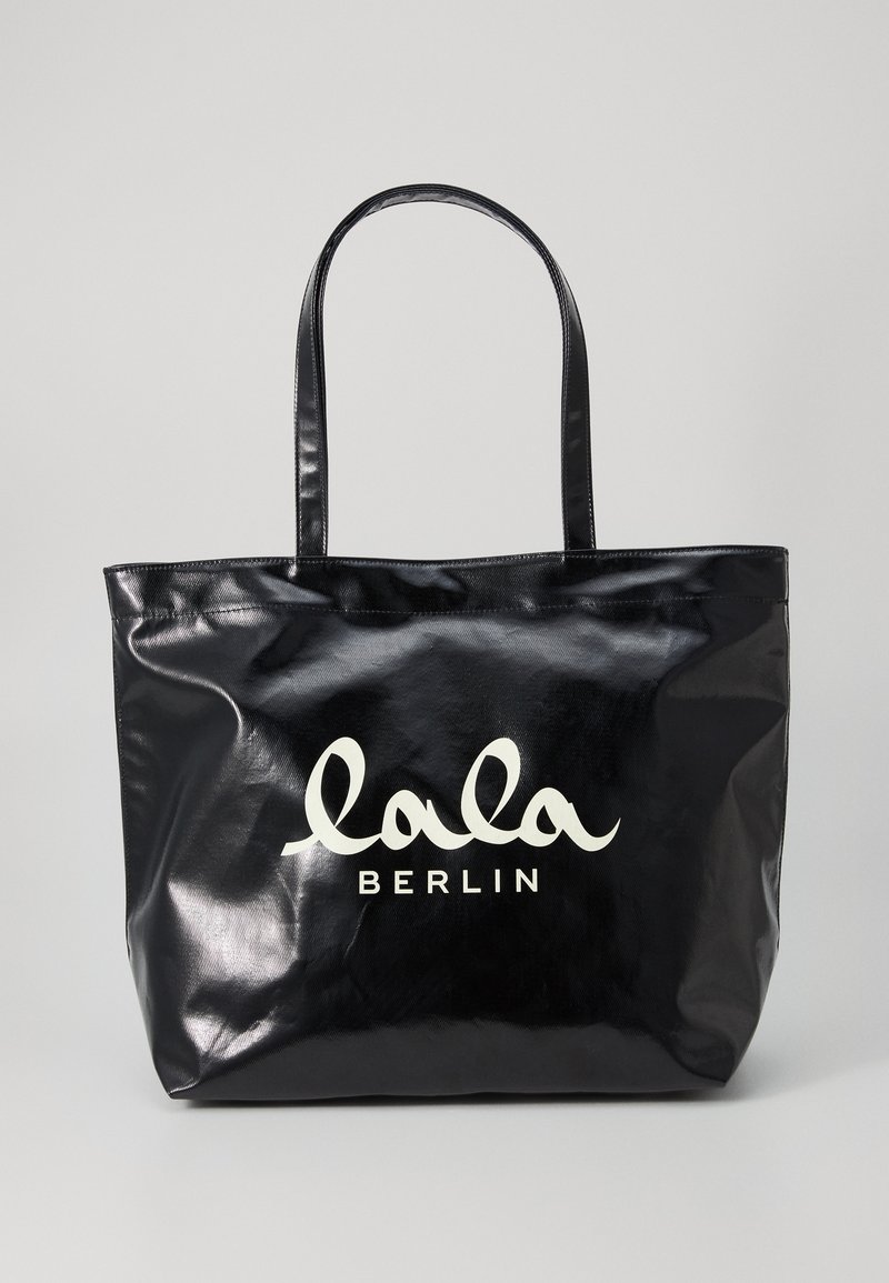 Borsa a tracolla nera lucida con due manici, con la scritta bianca "lala BERLIN" sul davanti. Texture liscia, forma rettangolare.