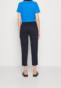 Blauw T-shirt met korte mouwen en een ronde hals, gecombineerd met marineblauwe cropped broek. De broek heeft een achterzak en is gemaakt van een soepele stof.