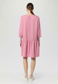 Rosa Freizeitkleid mit 3/4-Ärmeln, geraffter Taille und einem Schlüssellochverschluss im Rücken. Glattes Material und knielanges Design.