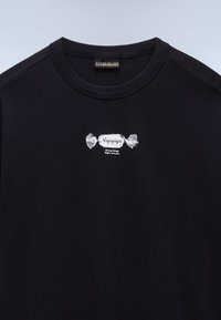 Sweat-shirt noir à col rond avec un petit motif de bonbon blanc et le texte "Napapijri" ainsi que "Wrong things. Right attitude." centré sur la poitrine.