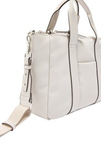 Beżowa torebka syntetyczna z podwójnymi uchwytami, odczepianym paskiem, srebrnymi okuciami i przednią kieszenią. Zawiera kontrastowe ciemne wykończenia.