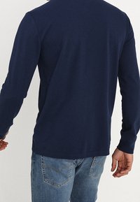 Mörkblå långärmad t-shirt av mjuk bomull. Har rund halsringning och en avslappnad passform med en slät yta och minimalistisk design.