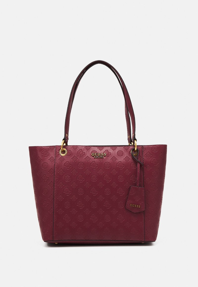 Borsa tote in pelle bordeaux della Guess con motivi a logo embossati, hardware dorato, doppi manici e un piccolo tag attaccato con il nome Guess.