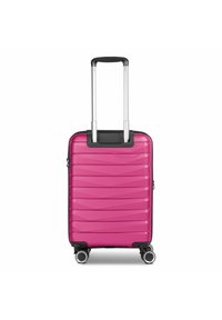 Valigia rigida di colore rosa brillante con un design testurizzato a onde, manico retrattile argentato e quattro ruote girevoli per una facile mobilità.