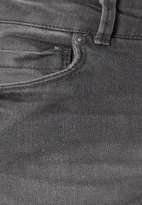 Donkergrijze denim jeans met een voorzak, metalen knoopsluiting en een gladde textuur met subtiele stiksel details.