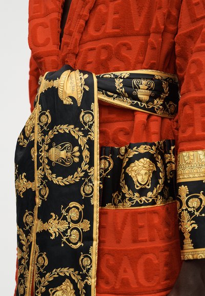Κόκκινη ρόμπα με υφή και ανάγλυφο κείμενο "VERSACE", λεπτομέρειες με ζώνη και μανσέτες σε μπαρόκ μοτίβο σε μαύρο και χρυσό με κεφάλια Μέδουσας.