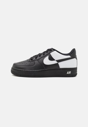 Czarno-białe niskie buty sportowe Nike Air Force 1 z białym logo Swoosh i czarną podeszwą, pokazane z boku na białym tle.