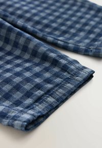 Plava karirana tkanina različitih nijansi s teksturiranim tkanjem. Rubovi su uredno završeni s blago izrezanim šavom.