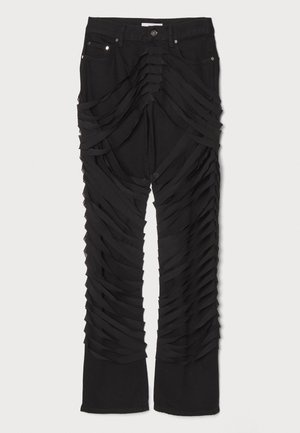 Czarne spodnie z warstwami tkanin biegnącymi wzdłuż nóg, z zamkiem błyskawicznym i zapięciem na guzik. Wykonane z miękkiego, teksturowanego materiału.