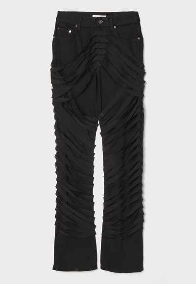 Pantalons noirs avec des bandes de tissu superposées le long des jambes, dotés d'une fermeture éclair et d'un bouton. Fabriqués dans un matériau doux et texturé.