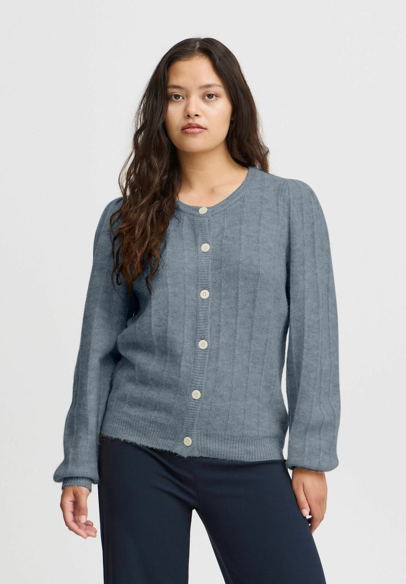 Pilkas tekstūruotas kardiganas su raštuotomis detalėmis, apvaliu kaklu ir ilgomis rankovėmis, su lengvais mygtukais priekyje. Atsitiktinis kirpimas.