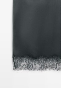 Dark gray fabric with a smooth texture, adorned with a scalloped edge of intricate black lace at the bottom.