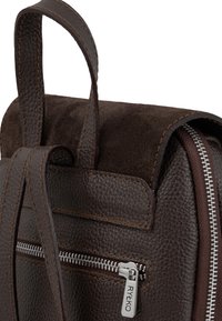 Zaino in pelle marrone con finitura texturizzata, patta in suede, cuciture a contrasto e una cerniera argentata con un tirante marchiato.