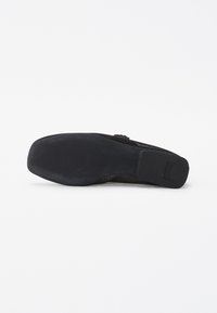 Scarpa piatta nera con suola in gomma testurizzata e tomaia in tessuto intrecciato. Il design è minimalista, senza hardware o accenti visibili.