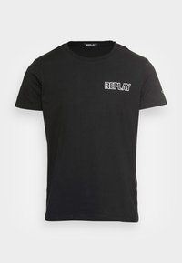 Camiseta negra de manga corta con cuello redondo y texto blanco "REPLAY" en el lado izquierdo del pecho, con un pequeño logo en la manga izquierda.