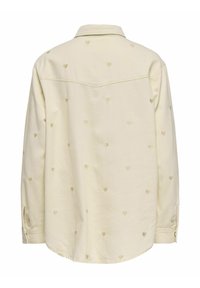 Chemise crème à manches longues avec boutons, ornée de petits motifs de cœurs brodés discrets répartis sur le dos et les manches.