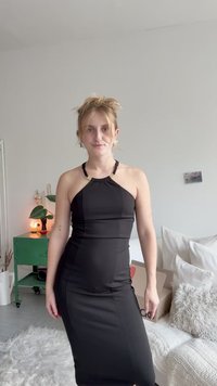 Črna brezrokavna obleka ima prilegajočo se silhueto, halter ovratnik z zlatimi poudarki in elastično tkanino, kar je idealno za laskav fit.