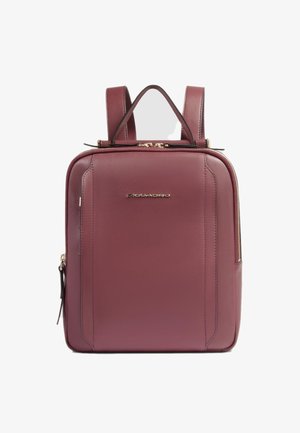 Mochila de cuero burdeos con herrajes en tono dorado, correas dobles, un asa superior y un compartimento principal con cremallera. Textura suave con detalles mínimos.