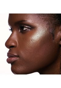 Profiel van een gezicht met een donkere huid, gladde textuur en een subtiele highlighter op de wang. Kenmerken zijn volle lippen en gedefinieerde jukbeenderen.