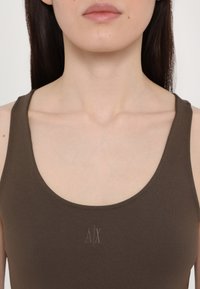 Top aderente marrone senza maniche con scollatura a forma di U. Presenta un sottile logo "A/X" ricamato in una tonalità leggermente più chiara. Texture liscia.