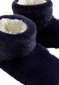 Comode pantofola in blu navy con una morbida superficie in pelliccia sintetica e una soffice fodera bianca; forma arrotondata con un design a risvolto.
