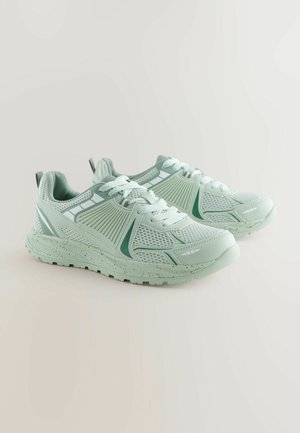 Ljusgröna träningsskor med nätsektioner, texturerade överdrag och en prickig sula. Snörningsdesign och bakre dragflik för enkel påtagning.