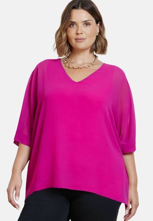 Fuchsia blouse met een V-hals, korte, verlaagde mouwen en een gebogen zoom. Gemaakt van lichtgewicht materiaal. Gecombineerd met een stevige gouden ketting.