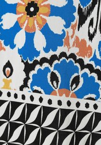 Bunt bedruckter Stoff mit einem floralen Design in Blau, Orange und Weiß, mit kräftigen schwarzen Akzenten und geometrischen Mustern am unteren Rand.