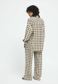 Brown and beige checkered button-up shirt and matching pants made of soft fabric. Relaxed fit with wide sleeves and flared legs.