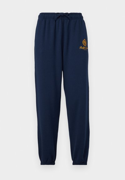 Navy sweatpants made of soft fabric, featuring an elastic waistband with a drawstring, elastic cuffs, and an embroidered logo on the thigh.