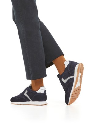 Zapatillas de ante azul marino con acentos blancos, que presentan un upper texturizado, una suela de goma y un collar acolchado para mayor comodidad.