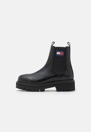 Sort læderankelstøvle med elastiske sidepaneler, meget slidstærk sål, trækstropper og et Tommy Jeans-logo på ydersiden.