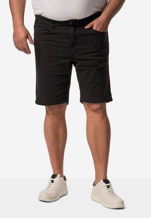 Shorts noirs en tissu léger avec une coupe droite et des passants de ceinture, associés à des baskets claires avec des accents noirs.