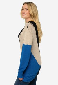 Maglione a maglia con un design a blocchi di colore in beige, nero e blu. Presenta maniche lunghe e una vestibilità comoda con polsini e orlo a costine.