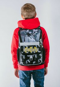 Zaino nero a tema Batman con una grafica di Batman, logo giallo a forma di pipistrello e motivi a pipistrello. Spallacci regolabili e chiusura anteriore con fibbia.