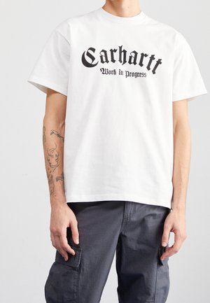 Weißes Baumwoll-T-Shirt mit auffälligem schwarzen "Carhartt"-Text und dem Slogan "Work in progress". Kurze Ärmel und lockere Passform. Glatte Textur.