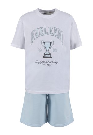Biele tričko s krátkym rukávom s grafikou trofeja, textom „"KARL KANI 1989"“ a svetlomodrými šortkami.