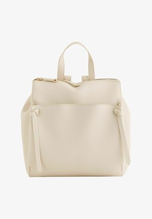 Bolso de cuero color crema con asas superiores, un bolsillo frontal y un cierre de cremallera dorado en el centro superior.