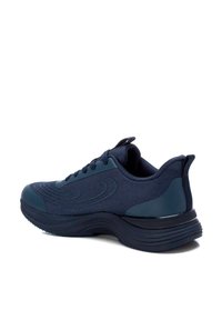 Zapatilla deportiva de color azul marino con parte superior de malla texturizada, suela acolchada y forma redondeada. Presenta cordones prominentes y un talón reforzado.